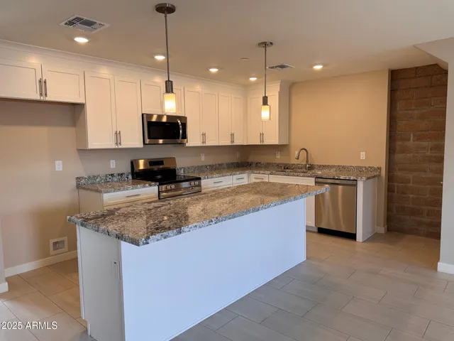 a kitchen with stainless steel appliances granite countertop a sink a stove and a refrigerator