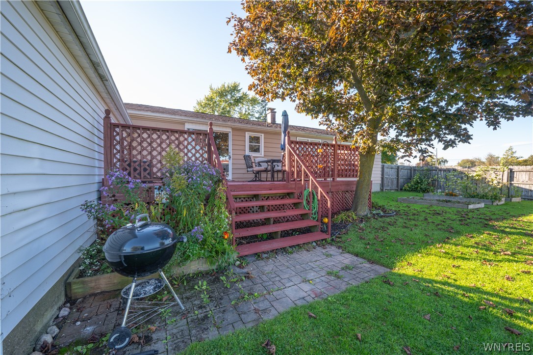 6463 Ward Road Sanborn, NY 14132 - Photo 43 of 49 An elevated wood deck overlooks the grassy backyard and garden beds.
