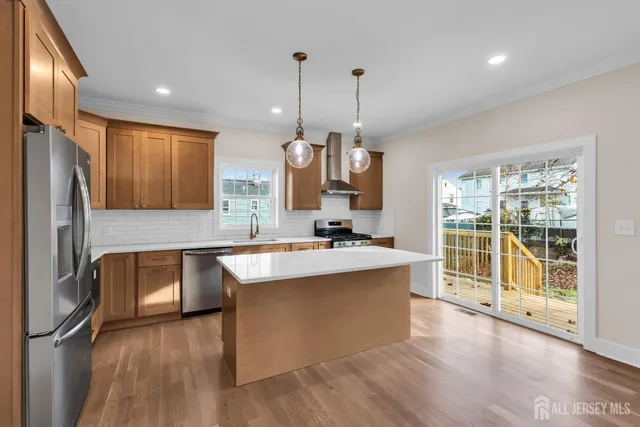 a large kitchen with kitchen island a large counter top a sink stainless steel appliances and cabinets