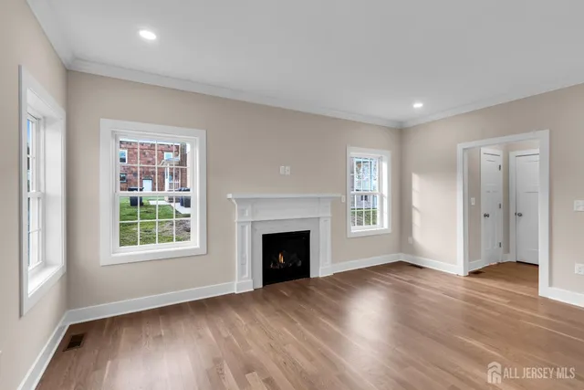 an empty room with wooden floor fireplace and windows