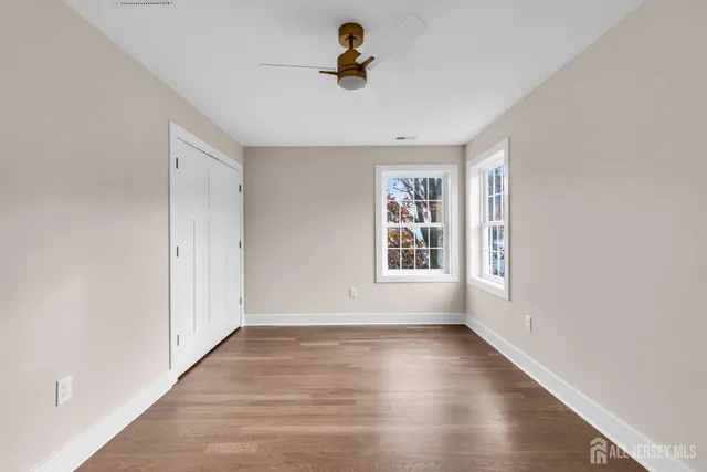 an empty room with wooden floor cabinet and windows