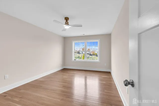 an empty room with wooden floor chandelier fan and windows