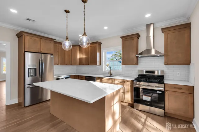 a kitchen with stainless steel appliances a stove a sink a refrigerator a center island a stove and a sink