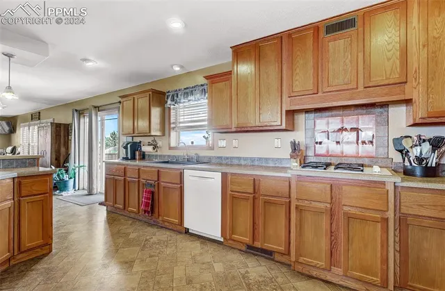 a kitchen with granite countertop a sink dishwasher stove and cabinets