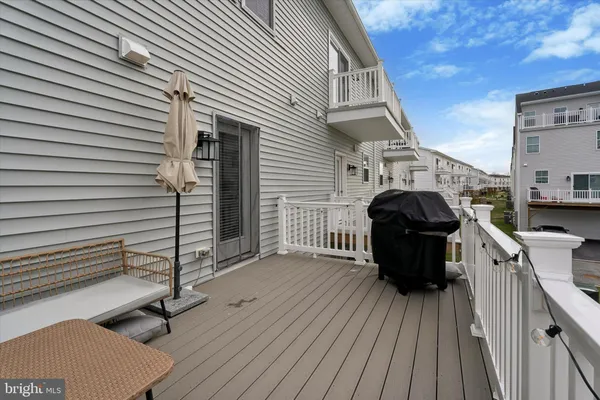 a view of a roof deck with table and chairs a barbeque with wooden floor and fence