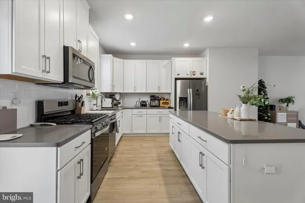 a kitchen with granite countertop white cabinets and white stainless steel appliances