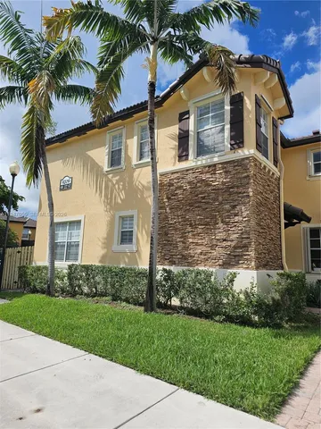 front view of a house with a yard and palm trees