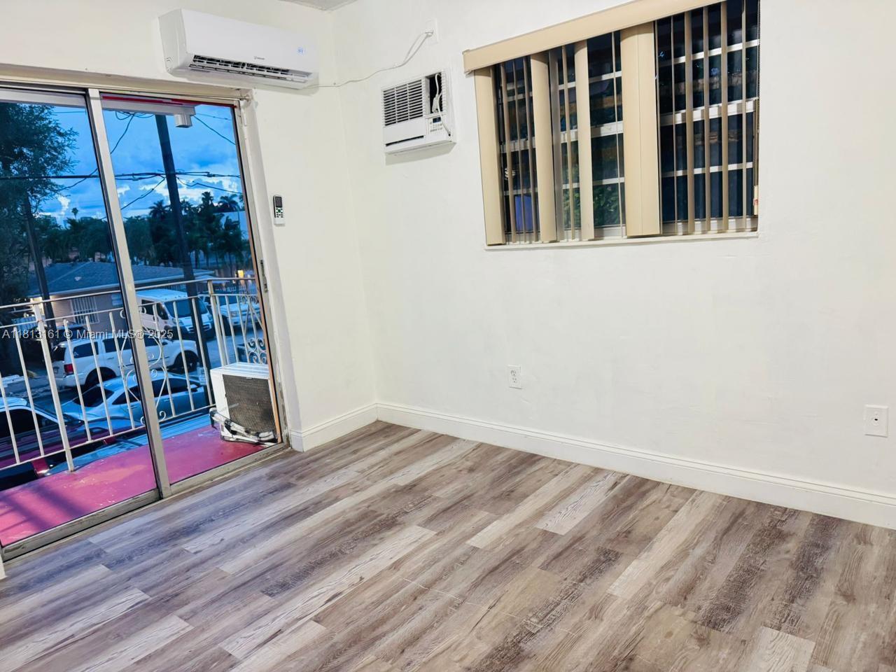 932 Northwest 5th Street, Unit 4 Miami, FL 33128 - Photo 4 of 16 a view of an empty room with wooden floor and windows
