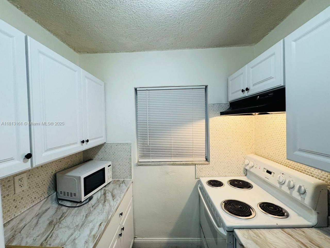 932 Northwest 5th Street, Unit 4 Miami, FL 33128 - Photo 7 of 16 a kitchen with granite countertop a sink and a stove top oven
