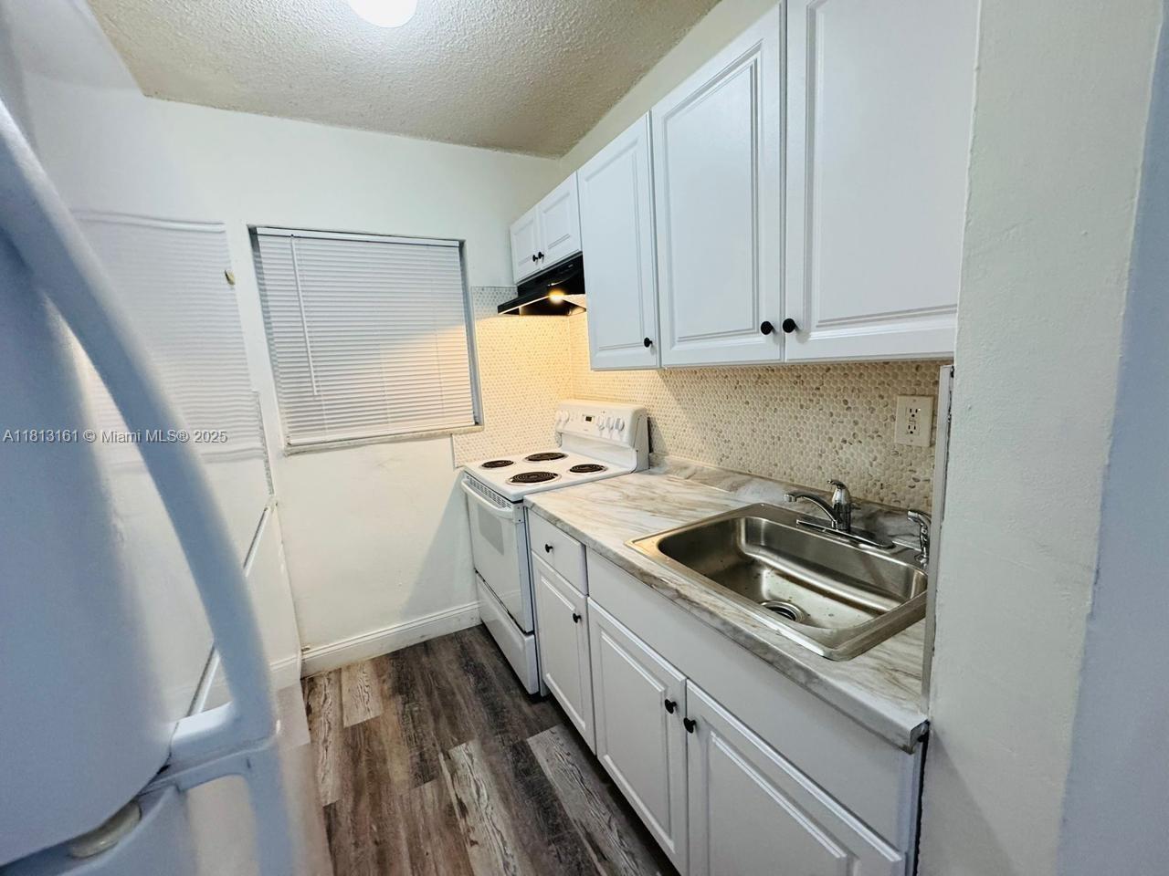 932 Northwest 5th Street, Unit 4 Miami, FL 33128 - Photo 9 of 16 a kitchen with a sink stove and cabinets