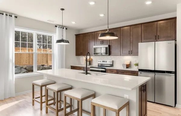 a kitchen with stainless steel appliances a stove a refrigerator a sink and a dining table with chairs