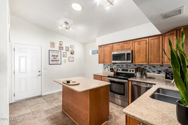 a kitchen with stainless steel appliances granite countertop a stove top oven a sink dishwasher a dining table and chairs with wooden floor