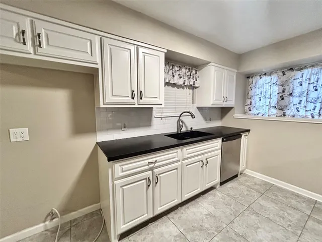 a kitchen with granite countertop white cabinets and sink
