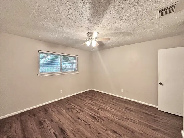 a view of a room with wooden floor and a ceiling fan