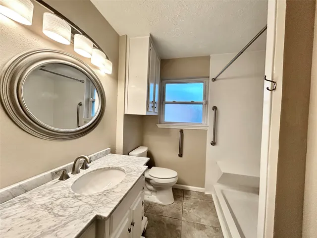 a bathroom with a granite countertop toilet a sink and a mirror