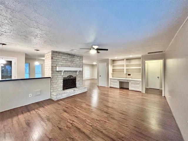 a view of a livingroom with a fireplace a ceiling fan and windows