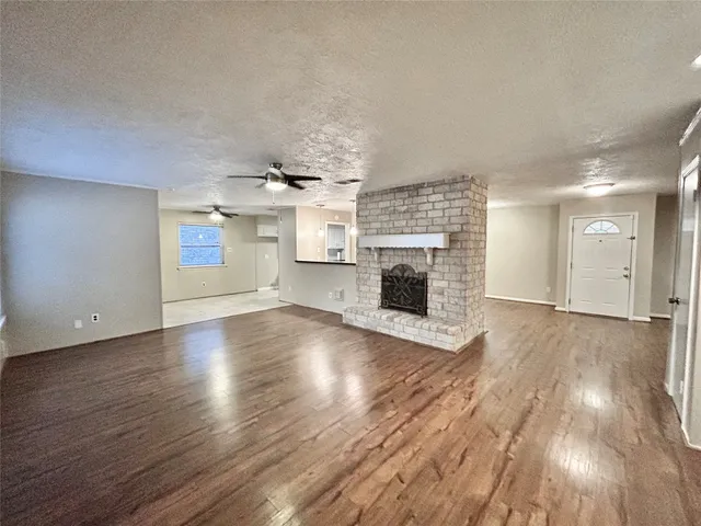 an empty room with wooden floor fireplace and windows