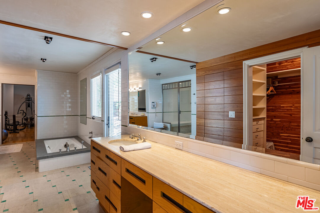 22148 Pacific Coast Highway Malibu, CA 90265 - Photo 17 of 28 a spacious bathroom with a granite countertop sink and a large mirror