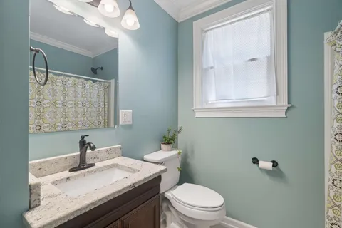 a bathroom with a granite countertop sink a toilet and a mirror