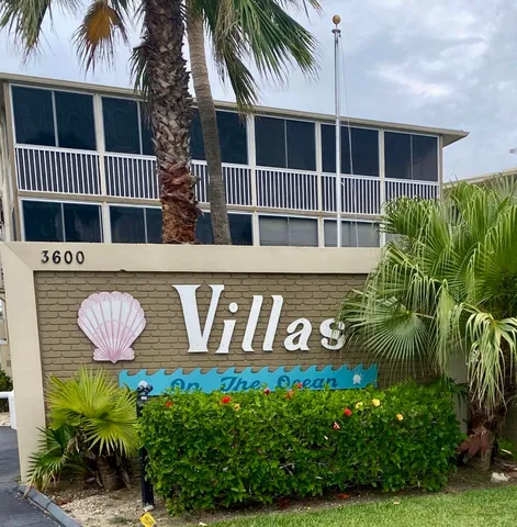 a front view of multi story residential apartment building with yard and sign board