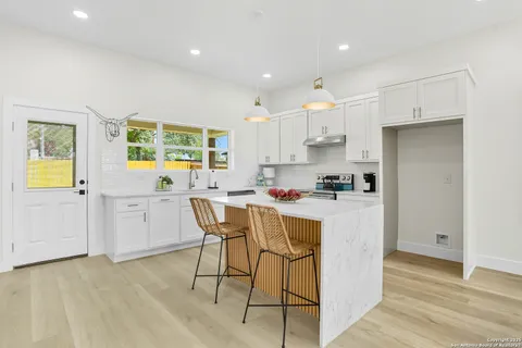 a kitchen with a sink a stove a refrigerator cabinets and a dining table