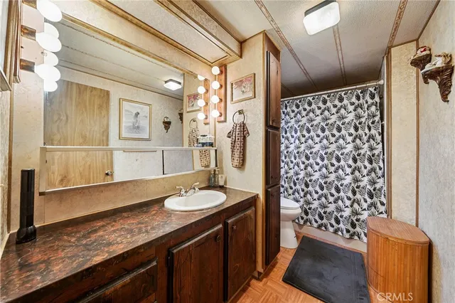 a bathroom with a granite countertop sink a toilet and shower curtain