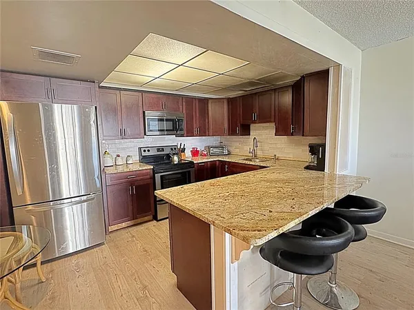 a kitchen with stainless steel appliances granite countertop a refrigerator a sink dishwasher a stove with wooden cabinets