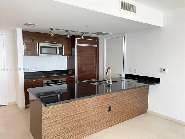 a view of kitchen with stainless steel appliances wooden floor and counter top space