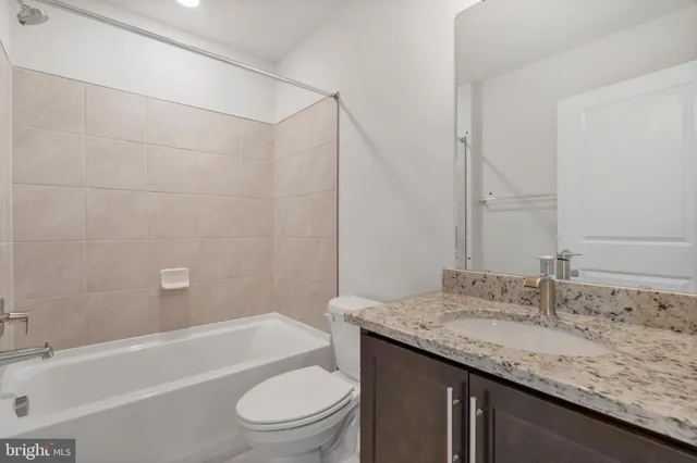 a bathroom with a granite countertop sink a toilet and bathtub