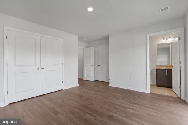 a view of an empty room with wooden floor and closet