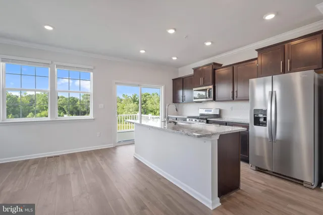 a kitchen with stainless steel appliances granite countertop a refrigerator a sink dishwasher a stove and a refrigerator with wooden floor