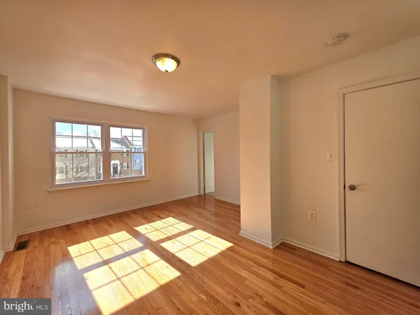 a view of an empty room and window and wooden floor