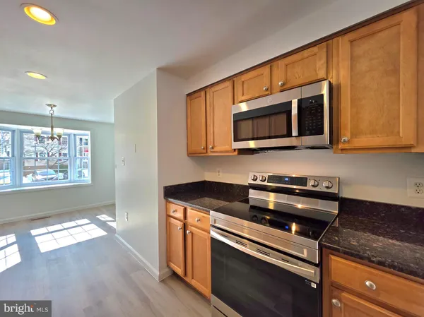 a kitchen with stainless steel appliances granite countertop a stove a microwave and wooden cabinets