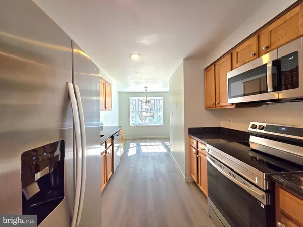 a kitchen with stainless steel appliances granite countertop a refrigerator and wooden floor