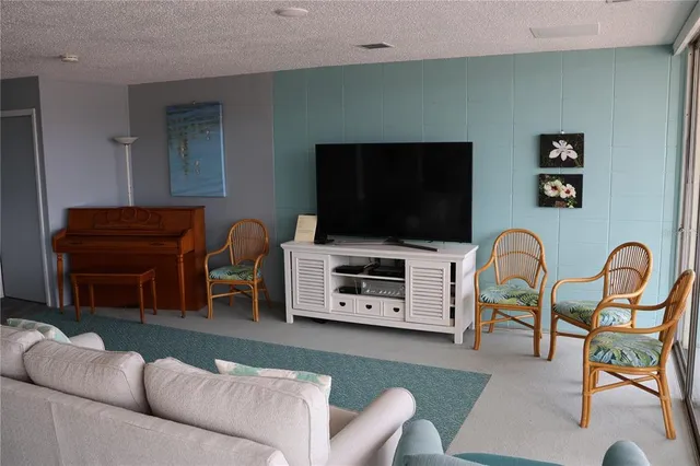 a living room with furniture a flat screen tv and kitchen view
