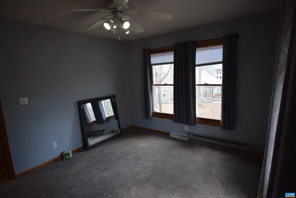 an empty room with chandelier fan and windows