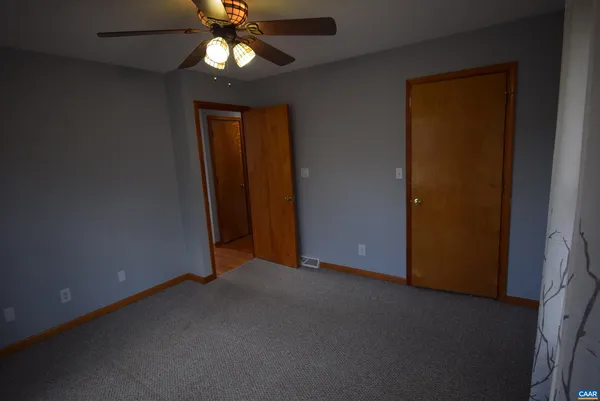 an empty room with closet and a chandelier fan