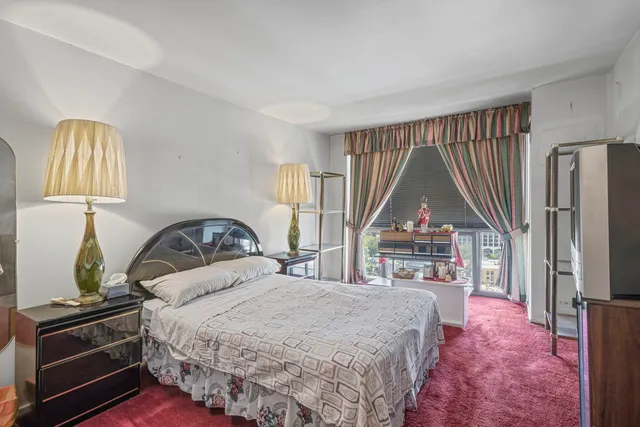 a bedroom with a bed next to a window and a flat tv screen