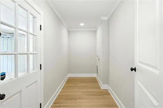 a view of a hallway with wooden floor and a bathroom