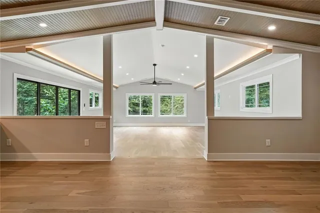 a view of an empty room with wooden floor and windows