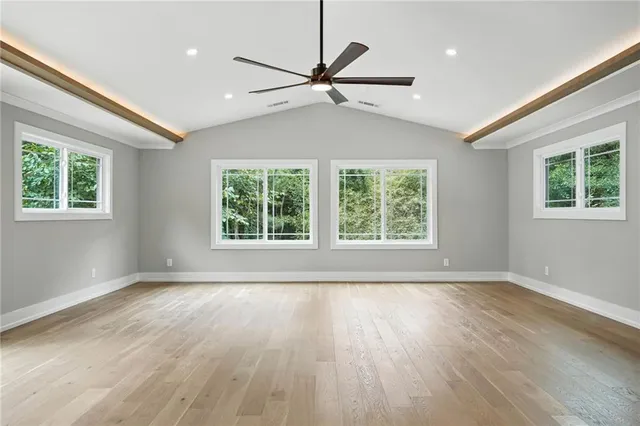 an empty room with wooden floor windows and fan