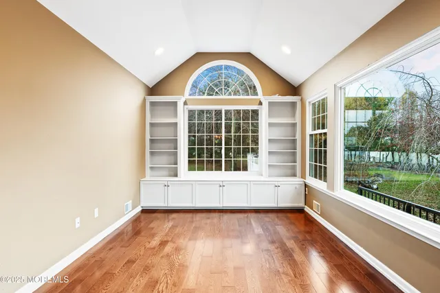 a view of an empty room with a large window and wooden floor