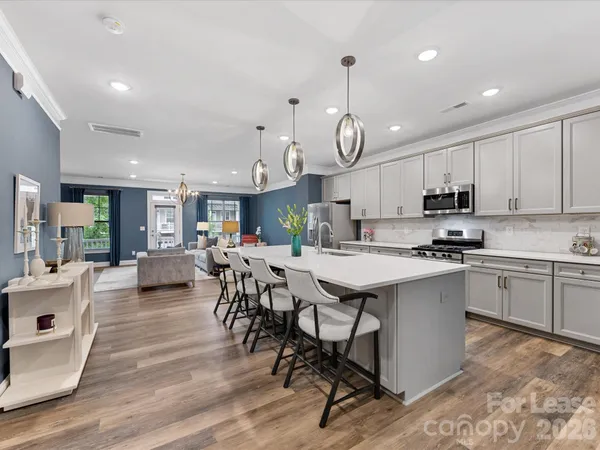 a open kitchen with stainless steel appliances granite countertop a stove a refrigerator a kitchen island a dining table and chairs with wooden floor