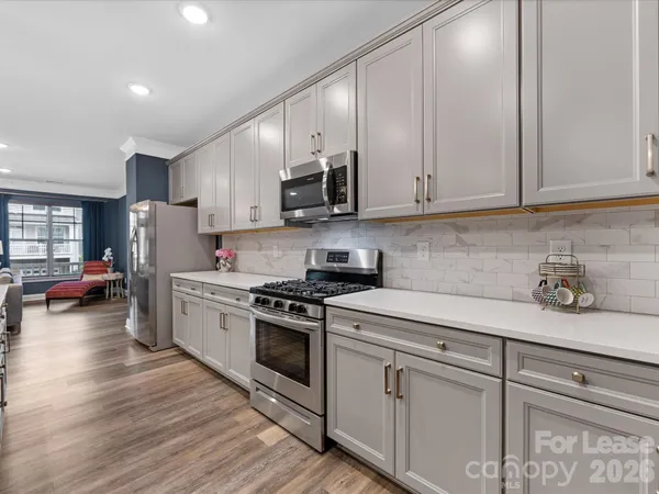 a kitchen with stainless steel appliances granite countertop a stove a sink dishwasher and a refrigerator with wooden floor