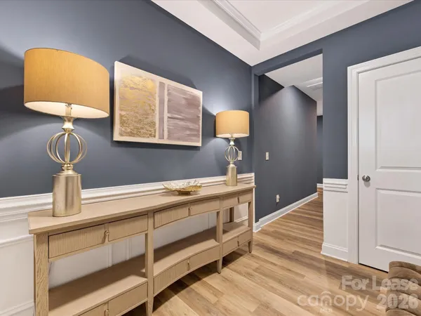 a view of a hallway to a room with wooden floor cabinet and a lamp