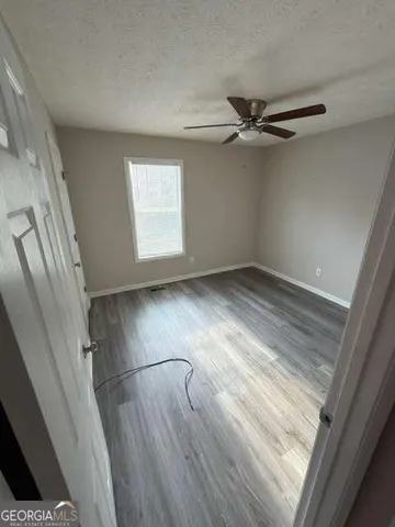 an empty room with wooden floor fan and windows