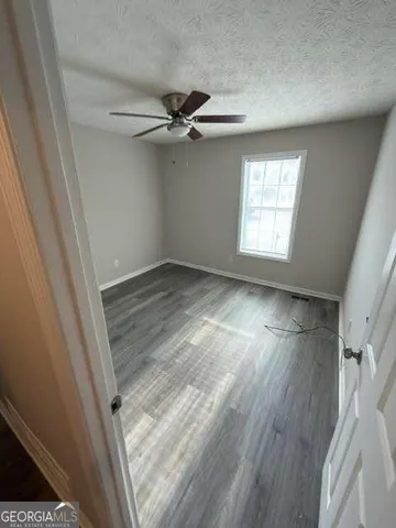 a view of empty room with wooden floor and fan
