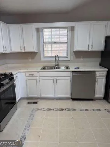 a large kitchen with a stove a sink a window and cabinets