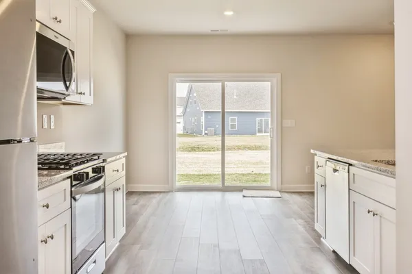 a view of kitchen with wooden floor electronic appliances and windows