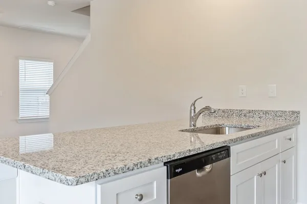 a kitchen with granite countertop a sink and a white cabinets
